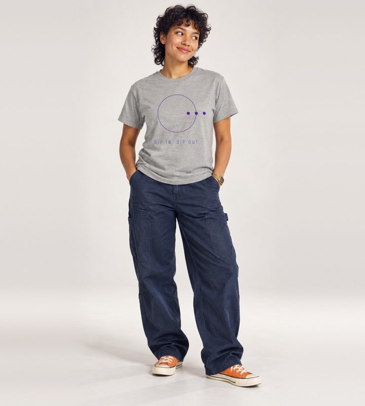 A woman in a grey tee with a ring and three dots